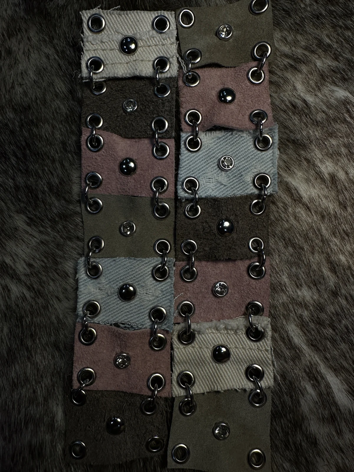 Pink, gray and brown leather panels joined by silver rings, with mixed metal studs.
