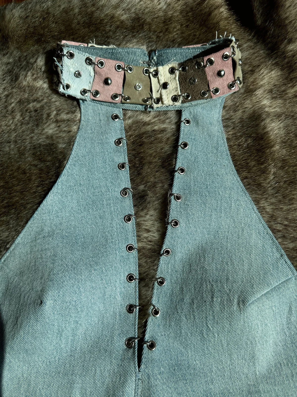 Reworked denim halter top with an open front, metal eyelets and a patchwork leather neckline.